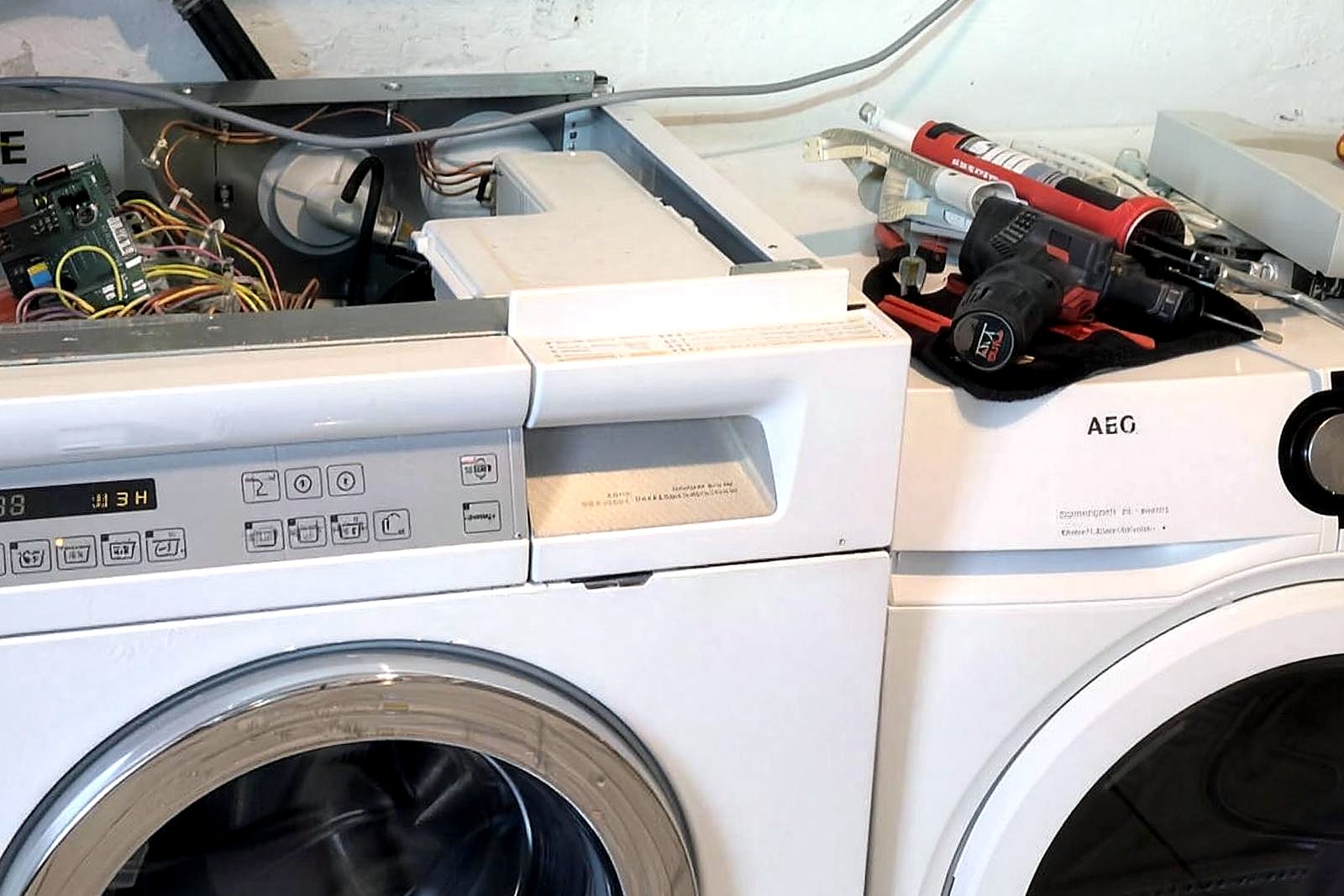 Werkzeug, Prüfgerät und geöffnete Steuerelektronik einer Waschmaschine während der Reparatur