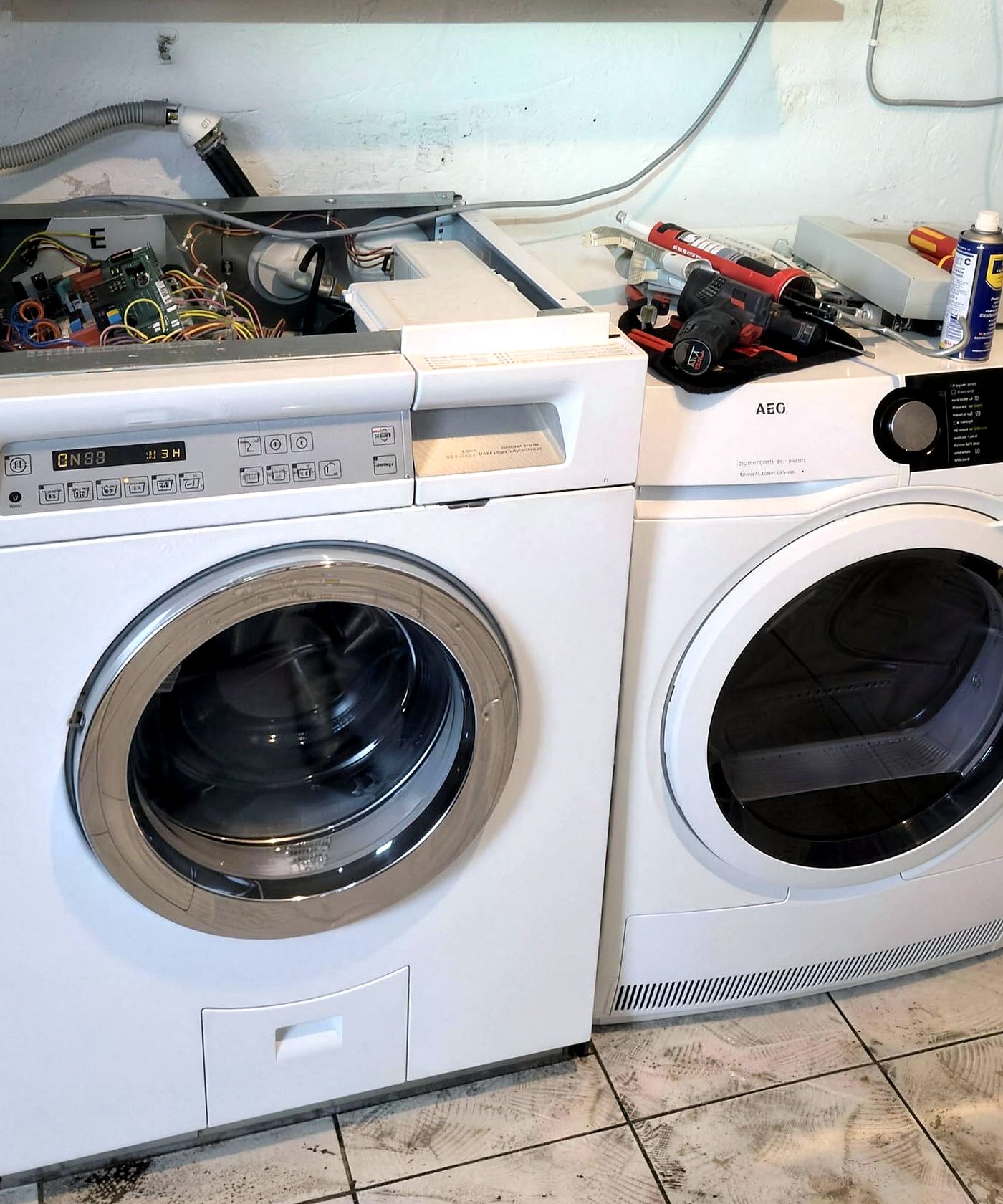 Geöffnete Waschmaschine während der Reparatur vor Ort – Blick auf Steuerelektronik und Werkzeug