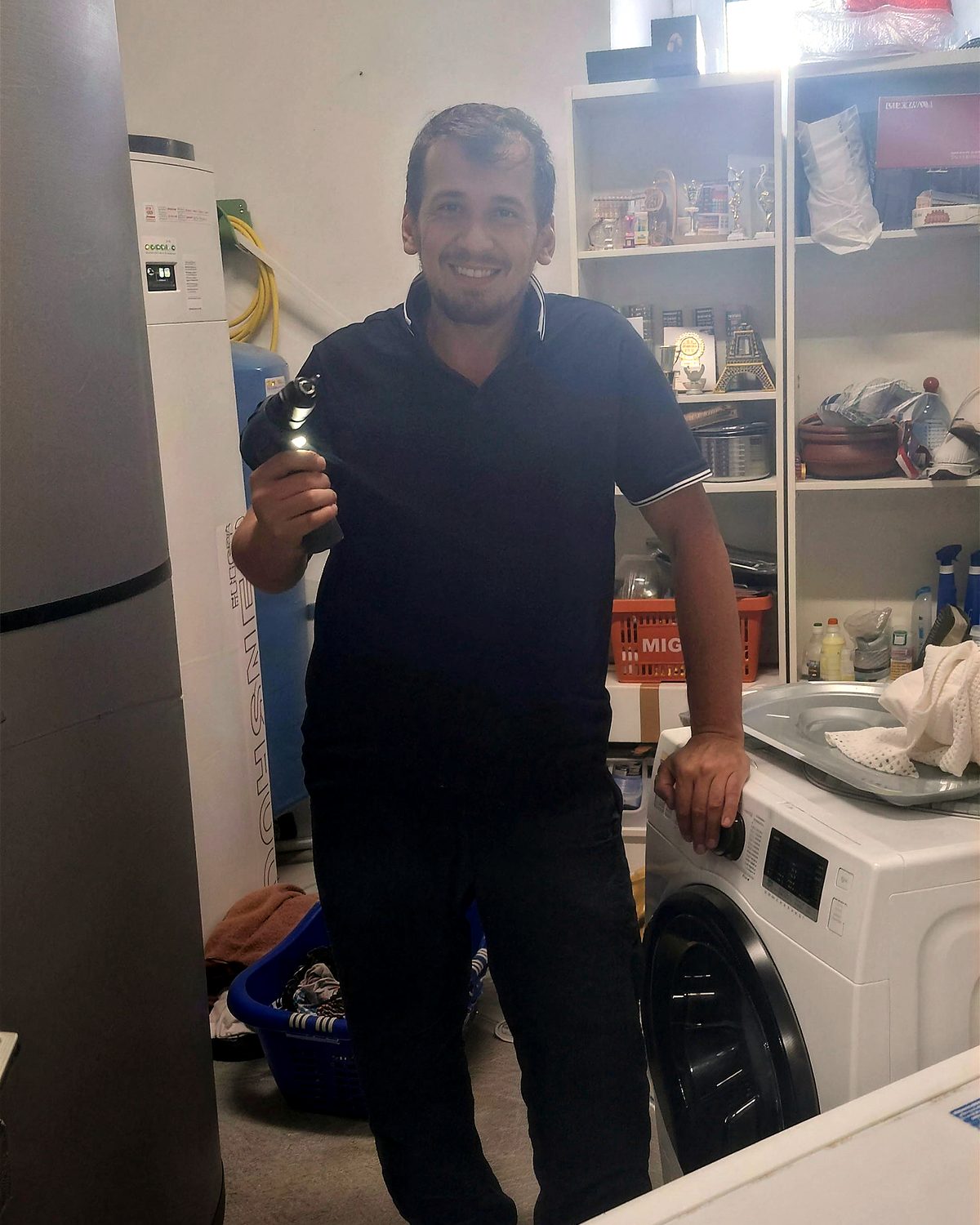 Techniker mit Prüfleuchte bei der Reparatur einer Waschmaschine vor Ort